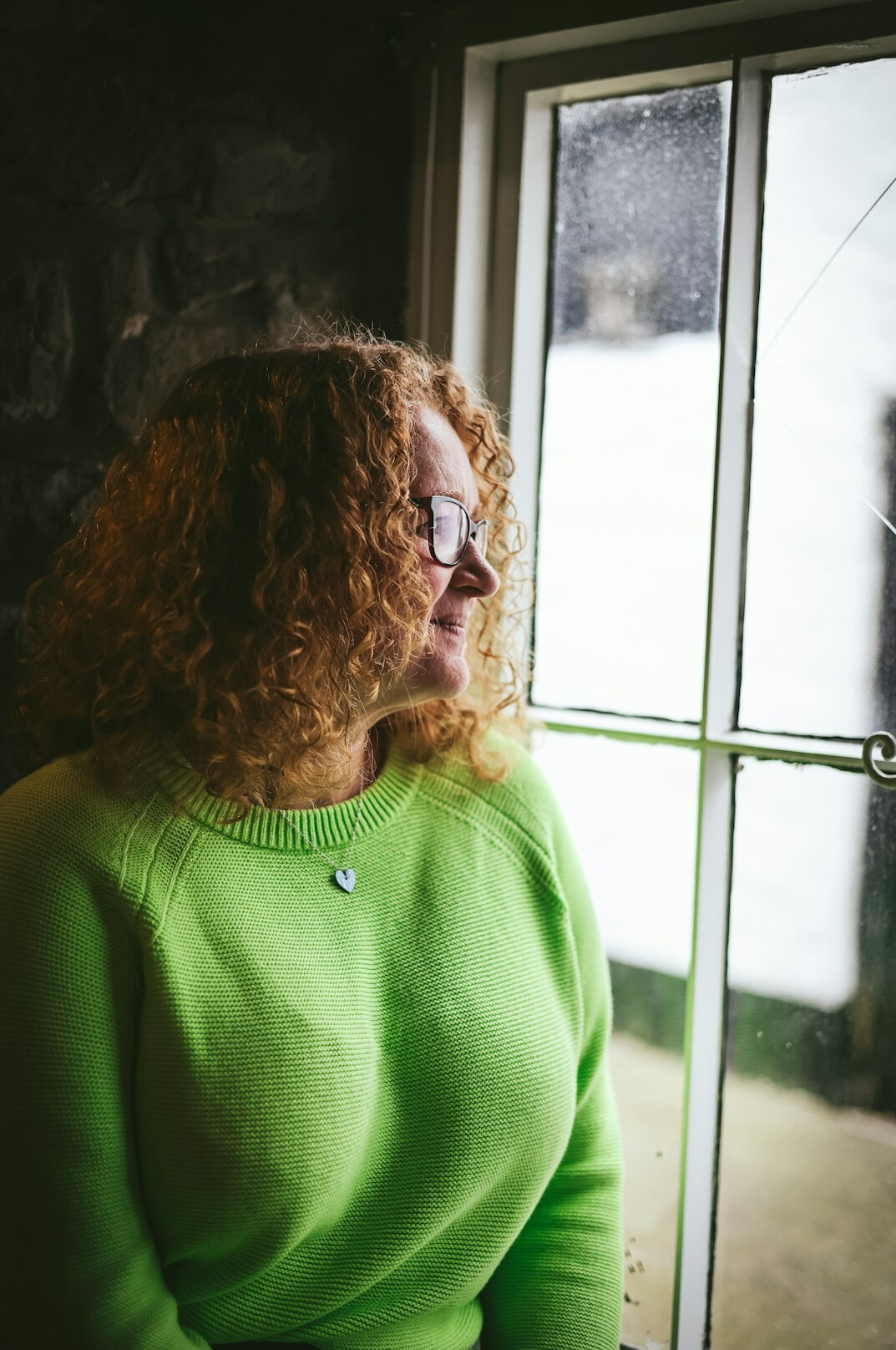 Person reflecting quietly while looking out a window